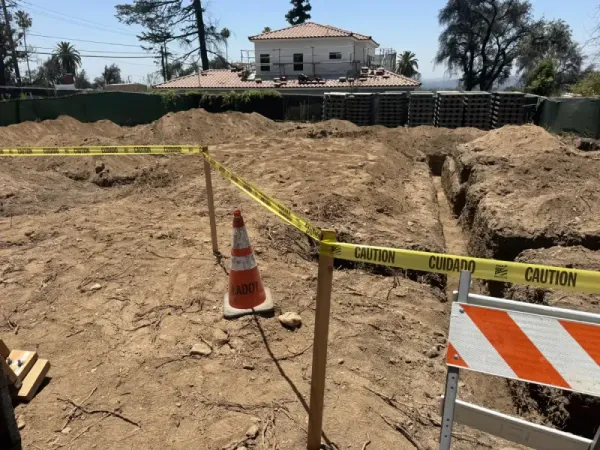 Concrete water meter and utility box with cleanout fitting installed at fire rebuild property, showing underground water service infrastructure connection for Altadena hillside home.