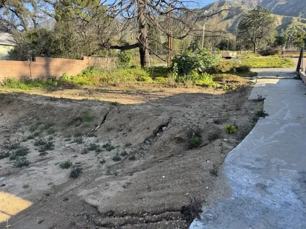 Post-fire Altadena lot with eroded terrain and concrete walkway requiring drainage plan design