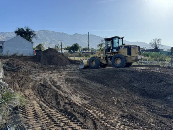 Yellow Caterpillar wheel loader on dirt construction site with mountain backdrop