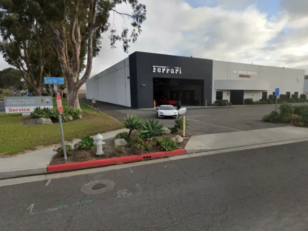 Ferrari and Maserati of Newport Beach service center showing modern commercial building, extensive asphalt paving, concrete curbing, landscaping, and fire hydrant integration