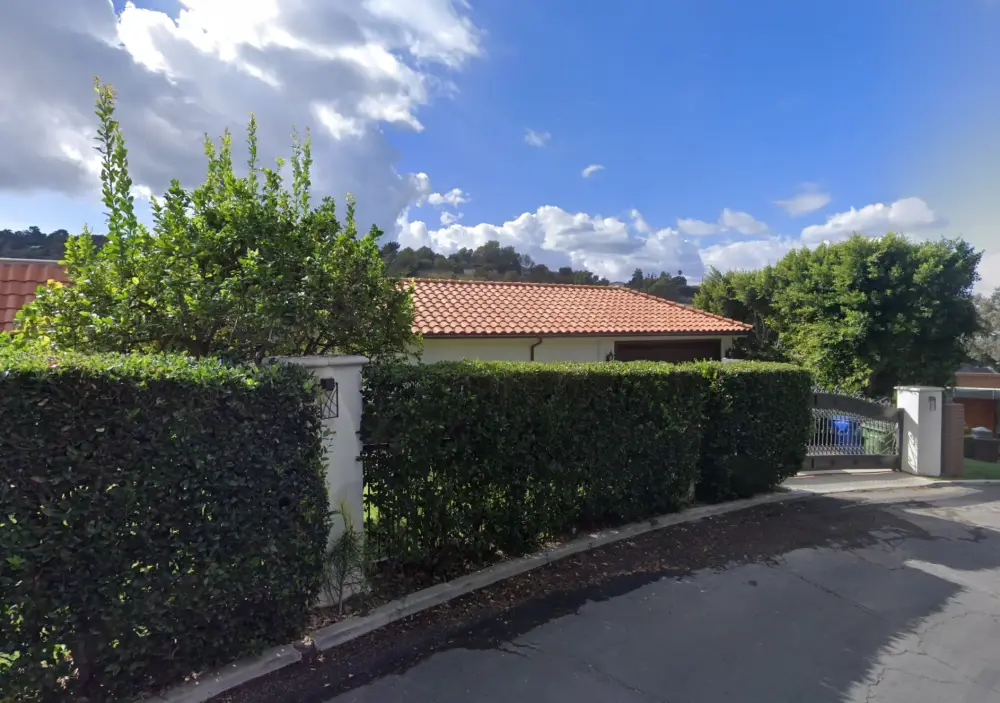 Sherman Oaks Completed Project - Mediterranean-style residence with terracotta tile roof, stucco walls, gated driveway entrance, and mature landscaping
