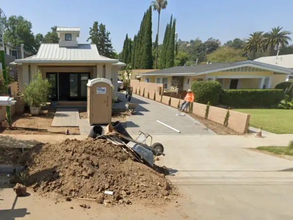 New construction residential property in South Pasadena featuring modern architecture, paver driveway, and retaining walls with neighboring yellow house visible