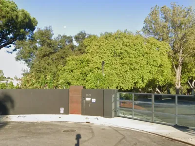 Modern residential entrance at 3523 Wrightwood Court with charcoal grey perimeter wall, Corten steel accent panel, glass driveway gate, and mature oak trees